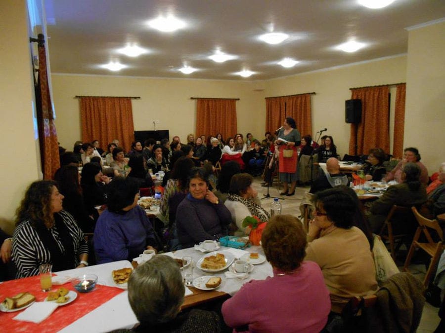 tourists sitting and tasting foods and listening to a woman speaking at the microphone